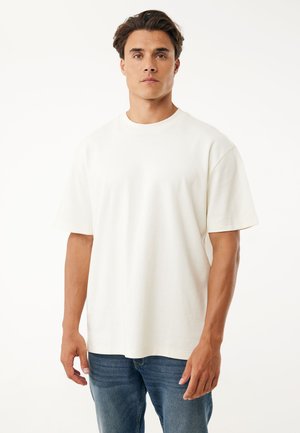 T-shirt blanc en coton à manches courtes, col rond et coupe décontractée. Le tissu semble doux, sans motifs ni logos visibles.