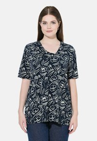 Blusa de manga corta azul marino con patrón de flores y hojas blancas, escote en V, corte relajado y textura suave. Se lleva con denim azul.