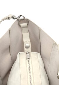 Valge nahast käekoti sisemus pehme voodriga, millel on lukuga tasku ja hõbedased detailid. Sisaldab eemaldatavat rihma.