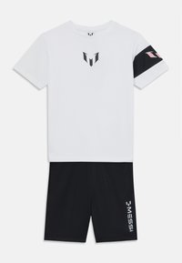 T-shirt blanc à manches courtes avec logo noir, associé à un short noir affichant le texte blanc 'MESSI'. Tissu doux, design sportif et accents de contraste.