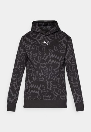 Melna kapucēta džemperis ar pelēkiem abstraktiem zigzag paraugiem un balto Puma logotipu vidū uz krūšu daļas, ribinātām aprocēm un apakšmalu.