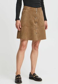 Brun semsket A-linje skjørt med høy midje, frontknapplukking og to store frontlommer. Kombinert med svarte loafers.