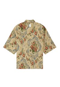 Camicetta a maniche corte in tessuto beige, caratterizzata da un motivo floreale in rosso, blu e verde, con colletto semplice e etichetta sul retro.
