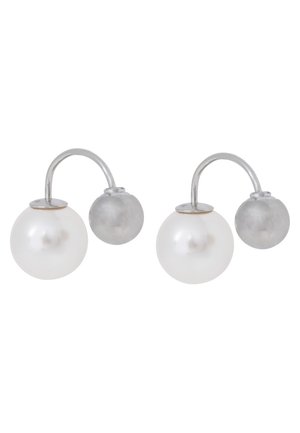 Hopeiset korvakorut, joissa kaareva tanko yhdistää suuren valkoisen helmen ja pienen hopeisen pyöreän helmen.