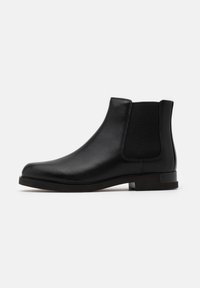 Black leather chelsea boot featuring elastic side panels, rounded toe, and a low stacked heel. Smooth texture with minimal stitching detail.