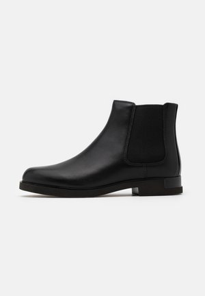 Svart läder Chelsea-boot med elastiska sidopaneler, rund tå och låg staplad klack. Slät textur med minimal sömnadsdetalj.