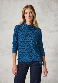 Blauwe top met kraag in een cowl-stijl, voorzien van een zwart geometrisch ruitpatroon, lange mouwen en verstelbare zijstrikken. Gemaakt van een zachte, gestructureerde stof.