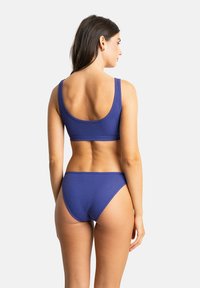Ensemble de bikini bleu à côtes comprenant un haut à encolure dégagée et un bas taille basse. Le tissu est lisse avec un léger brillant et un design minimaliste.