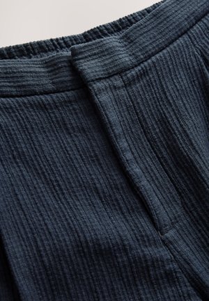 Mørkeblåt tekstureret stof med et ribbet mønster, med en elastisk talje med indsamlet kant og en flad frontdetalje.