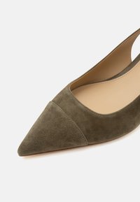 Chaussure plate femme à bout pointu en daim vert olive avec bride arrière et doublure intérieure beige sur fond blanc.