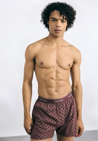 Calvin Klein vīriešu bokseri ar ģeometrisku rakstu bordo krāsā, ar zīmolu elastīgu jostasvietu, izgatavoti no mīksta auduma.