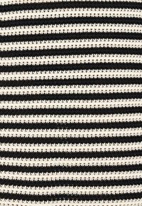 Μαύρο και άσπρο ριγέ πλεκτό ύφασμα με εναλλασσόμενες παχιές και λεπτές υφασματικές γραμμές.