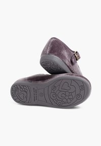 Zuecos de terciopelo morado con una hebilla de latón y suela de goma gris texturizada que presenta patrones florales y corazones. Parte superior suave con forma redondeada.