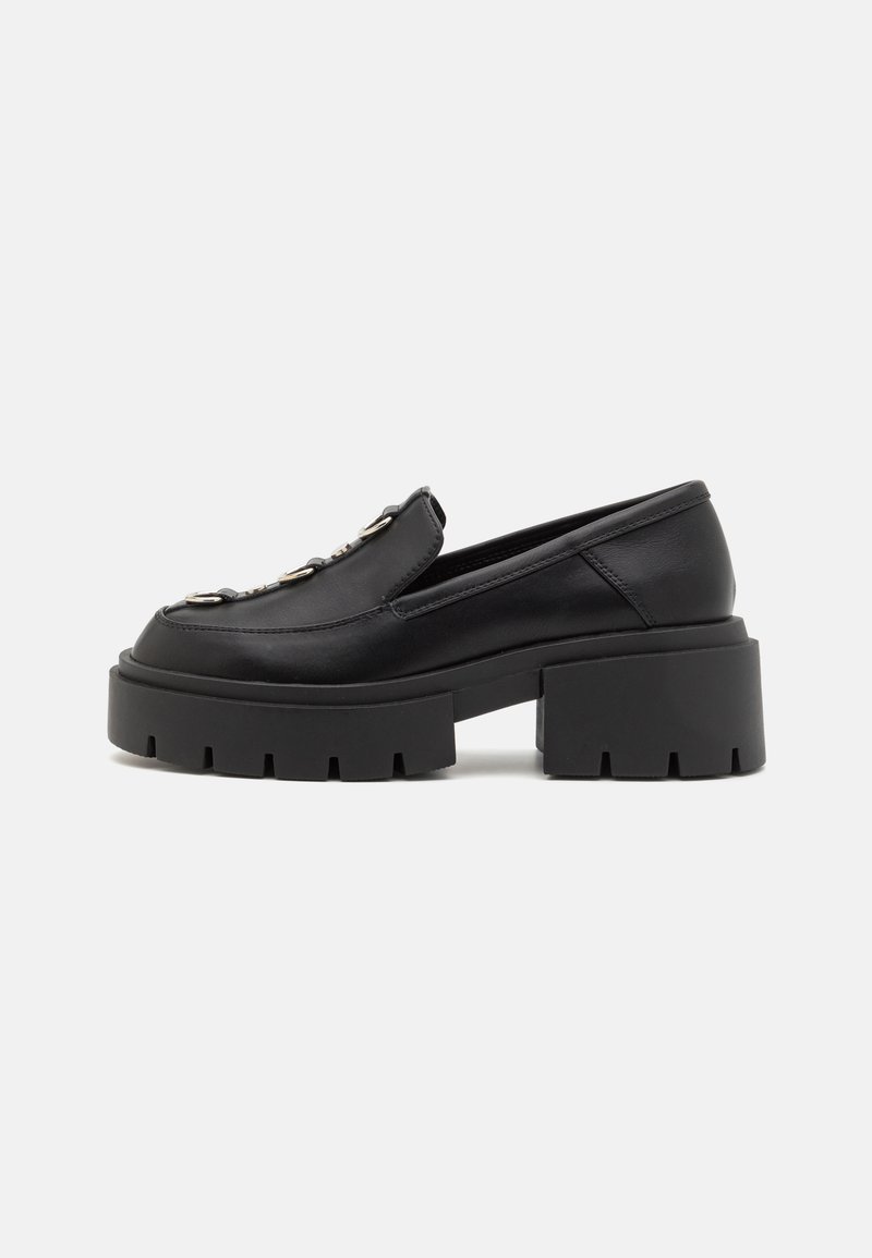 Mustat loafers, joissa on paksut, uritetut pohjat, sileä nahkainen yläosa ja koristeellinen hopeinen varuste vampin alueella. Määritelty muoto, jossa on pyöristetty kärki.