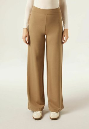 Pantalons beige à jambes larges en tissu doux et extensible avec une taille haute, présentant une texture lisse et sans fermetures visibles.