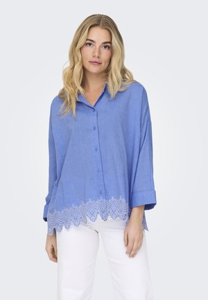 Chemise boutonnée bleu clair d'un fit décontracté, avec un ourlet en dentelle festonnée et des manches retroussées ; fabriquée en tissu tissé.