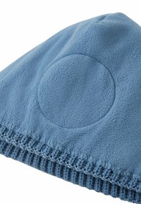 Niebieska czapka polarowa z zaokrąglonym wierzchem, teksturowaną powierzchnią i ryżowym splotem na dole. Posiada okrągły akcent po jednej stronie.