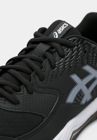 Černá atletická obuv s texturovaným svrškem, která má šedé logo a tkaničky, hladké detaily a polstrovanou podešev.