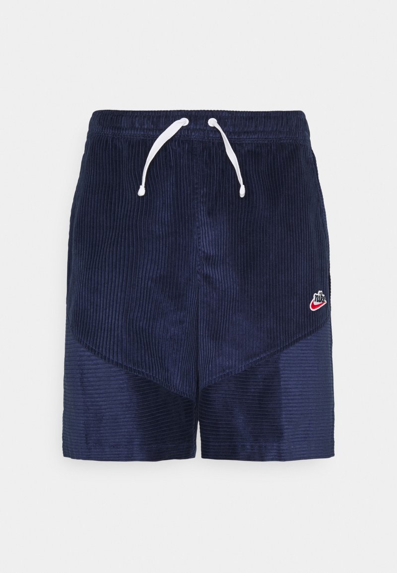 Marinblå kordshorts med elastisk midja, vita dragsnören och liten röd Nike-logga på vänster ben.