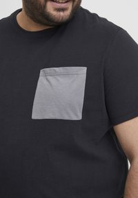 Sort bomulds T-shirt med en grå lomme. Korte ærmer, rund halsudskæring, afslappet design, blød tekstur og flotte syninger.