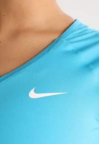Primer plano de una persona que lleva una camiseta Nike de color azul brillante con el logo de Nike en blanco en el pecho.
