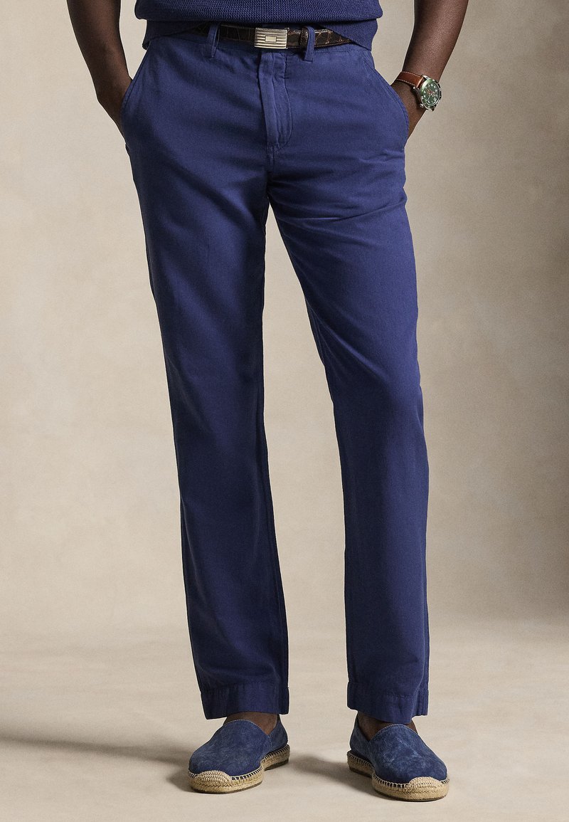 Donkerblauwe broek met een rechte pasvorm, gemaakt van lichtgewicht stof. Heeft een klassiek ontwerp met zijzakken en een subtiele glans.