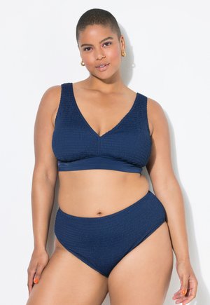Il set bikini blu navy presenta un tessuto testurizzato con un design arricciato, spalline larghe e un fondo a vita alta per una vestibilità confortevole.