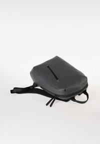 Zaino nero realizzato in materiale elegante e testurizzato con una forma rettangolare. Presenta una zip superiore, spallacci regolabili e una tasca frontale.