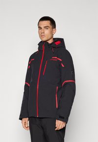 Jachetă neagră cu accente roșii, buzunare cu fermoar, glugă ajustabilă și material texturat. Prezintă logo-ul Spyder pe piept și pe braț.