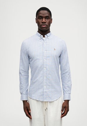 Långärmad skjorta med knappar i vitt med blå och röd rutmönster, med krage och en liten logotyp på bröstet. Utvecklad i bomull.