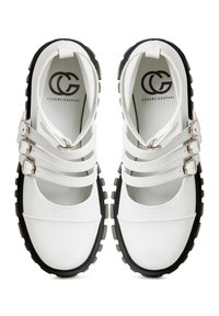 Le scarpe di pelle bianche presentano diverse cinghie incrociate e fibbie in argento, con una suola in gomma e punta rotonda. Logo del marchio visibile all'interno.