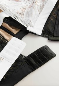 Trei sutienuri expuse: sutien alb din dantelă cu materiale negre și nude dedesubt. Prezintă bretele ajustabile și diverse tipuri de închidere cu cârlige.