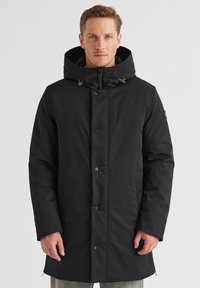 Schwarzer Parka mit Kapuze, aus einem glatten, wasserabweisenden Material. Verfügt über Knopfverschlüsse, Seitentaschen und hat einen leichten Glanz.