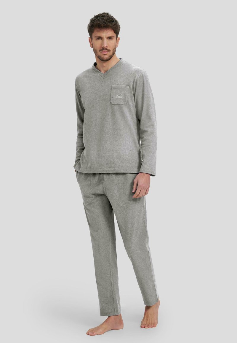Conjunto de loungewear gris en tejido suave, que incluye una camiseta de manga larga con un bolsillo en el pecho y pantalones a juego de corte relajado.