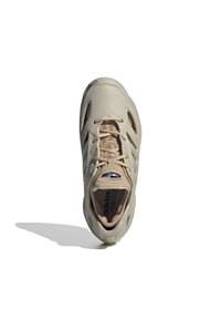 Beige urheilujalkine, jossa on tyylikäs synteettinen päällinen, verkkoventilaatio ja tasainen nauhajärjestelmä. Varustettu pehmustetulla sisäosalla ja tekstuurilla varustetulla pohjalla.