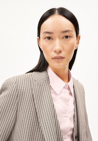 Gray striped blazer with notched lapels, single button, and two front pockets, paired with a light pink collared shirt. Smooth fabric texture.