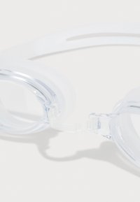 Lunettes de bain transparentes avec une sangle blanche flexible, des jointures en silicone souple et des verres clairs. Présentent un design ergonomique et aérodynamique.