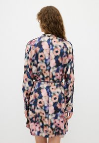 Långermad klänning i lätt tyg med ett flerfärgat blommönster i rosa, blått och svarta accenter; åtsittande midja med ett bälte.