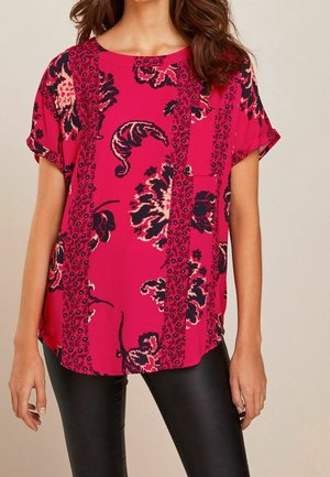 Blusa de manga corta, de color rosa fuerte, con patrones florales en azul oscuro y crema; tela ligera con un corte relajado y un escote redondo.