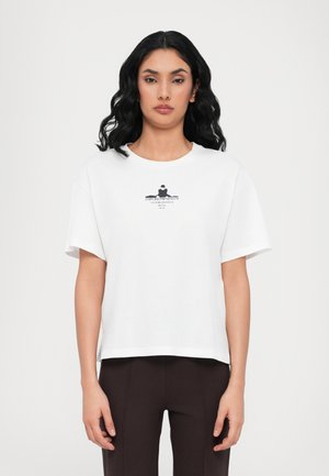 T-shirt en coton blanc à manches courtes, col rond et impression graphique avec texte et motif en noir sur le devant.