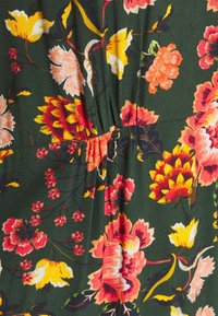 Stoff mit floralem Muster in Dunkelgrün, verziert mit großen pinkfarbenen, gelben und roten Blumen. Das Material wirkt leicht und hat eine strukturierte Oberfläche.