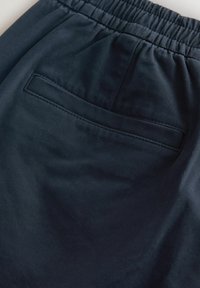 Námořnické modré kraťasy s elastickým pasem, s zadní kapsou s obdélníkovým otvorem a hladkým, strukturovaným materiálem.