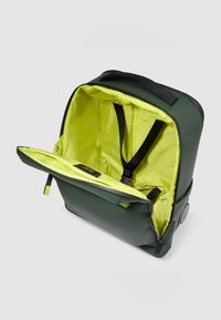 Zaino verde con esterno liscio e interno di un giallo brillante. Presenta spallacci regolabili e un compartimento con cerniera per un facile accesso.