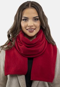 Écharpe rouge en tissu doux, drapée autour du cou. Présente une texture lisse et un design large, offrant chaleur et couverture.