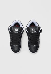 Un paio di sneakers Globe nere con suole bianche e interna bianca, viste dall'alto su uno sfondo chiaro e semplice.