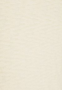 Texturerad kremfärgade tyg med en mjuk, vävd yta, som har subtila variationer i nyans och mönster, lämplig för kläder eller möbelklädsel.