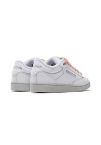 Sneakers bianchi in pelle con un accento testurizzato rosa. Presentano una suola in gomma grigia e un semplice design con lacci. Logo Reebok sul lato e sul tallone.