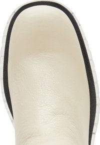 Chaussure en cuir crème avec une finition lisse, dotée d'un bord en caoutchouc noir et d'une semelle translucide. Design à bout rond.