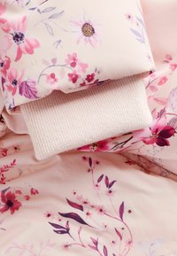 Blumenmusterstoff in verschiedenen Pinktönen mit geripptem Bündchen. Weiche Textur mit detaillierten Blumen und Blättern, die einen geschichteten Look erzeugen.