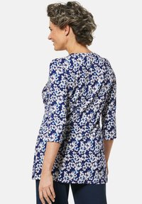 Marineblaue Bluse mit weißem Blumenmuster, runder Halsauschnitt und Dreiviertelärmeln. Hergestellt aus leichtem Stoff und mit lockerer Passform.